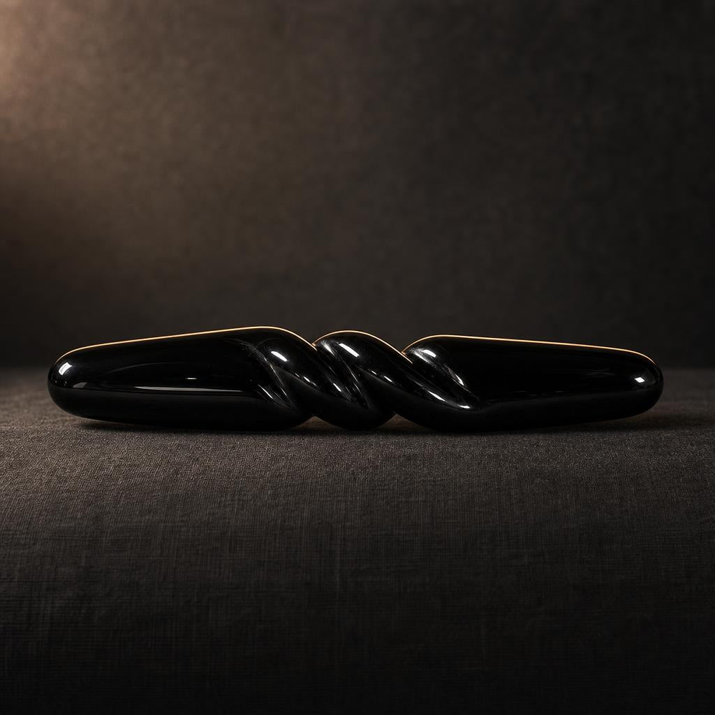 The Obsidian Bar seen from the side on charcoal linen, showing its full 18 cm length and carved spiral
