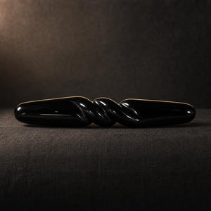 The Obsidian Bar seen from the side on charcoal linen, showing its full 18 cm length and carved spiral