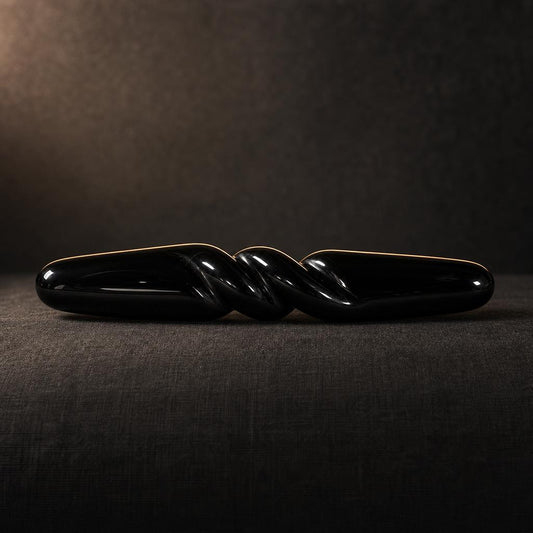 The Obsidian Bar seen from the side on charcoal linen, showing its full 18 cm length and carved spiral